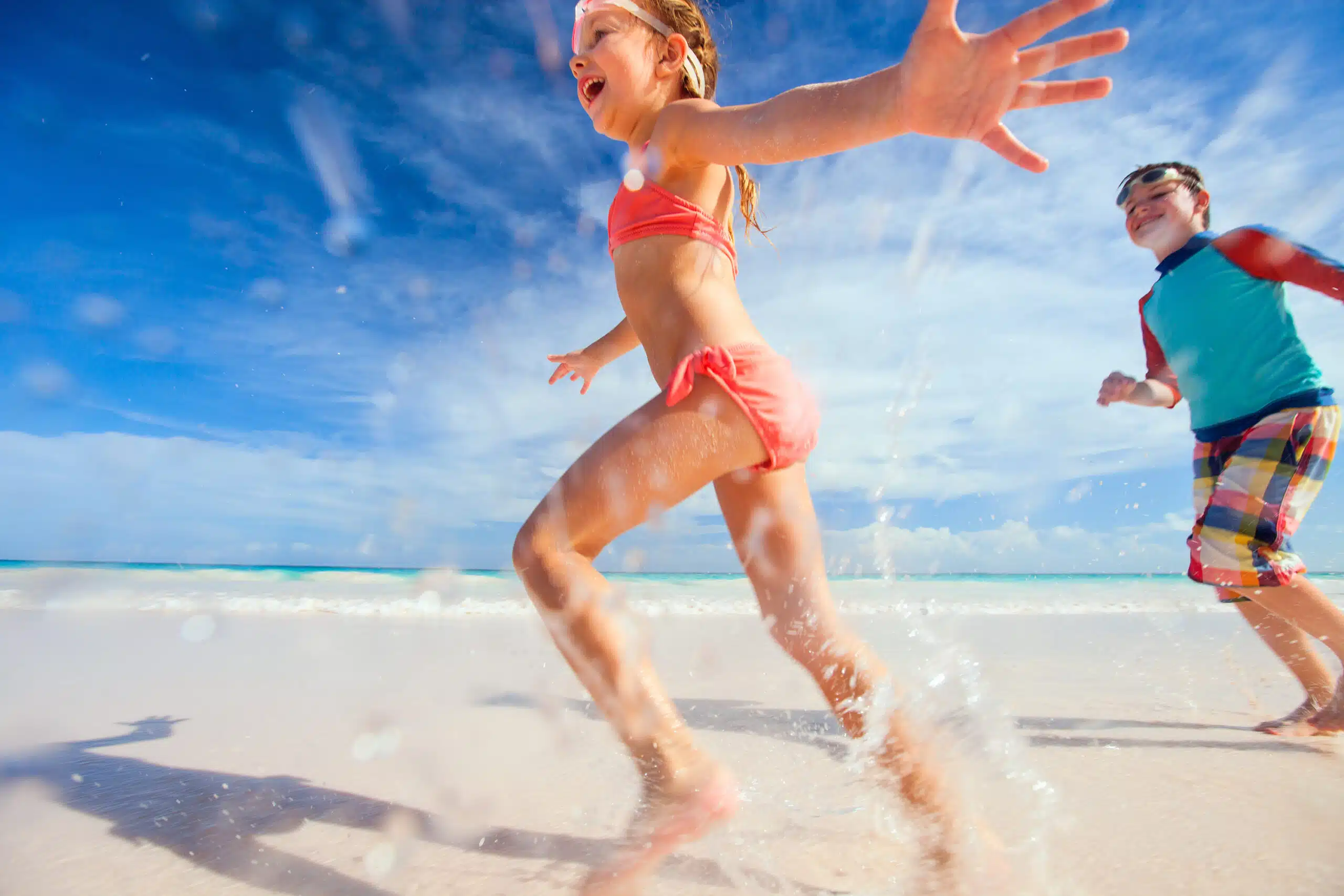 Happy kids running and jumping at Grace Bay Beach, Providenciales, Turks and Caicos