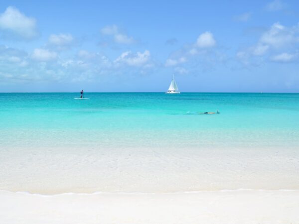 Looking out at Grace Bay in the Turks and Caicos Islands where there is a paddle boarder, snorkeler and sailboats.